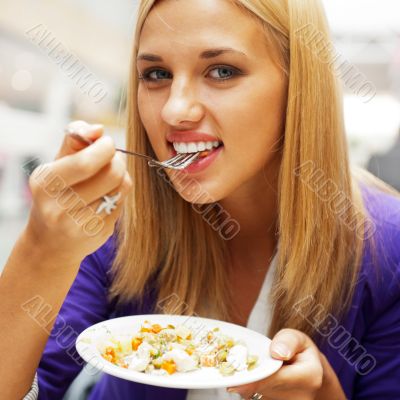 Closeup portrait of an attractive young woman eating fruit salad