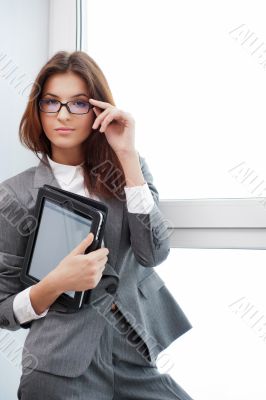 Smiling young business woman using tablet PC while standing rela