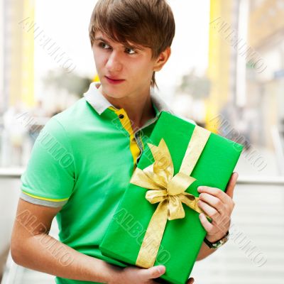 Portrait of young man inside shopping mall with gift box standin