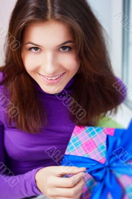 Delighted woman opening a gift sitting on the bean bag at home