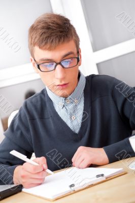 High school - Young male student write notes in classroom