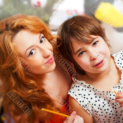 Mother and her daughter sitting together near christmas tree