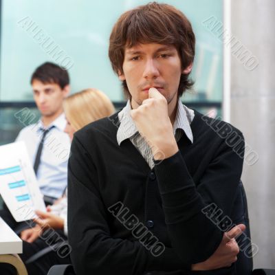 Portrait of a young business man sitting by his laptop in the of