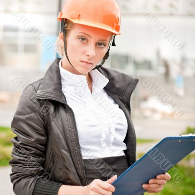 Young architect-woman wearing a protective helmet standing on th