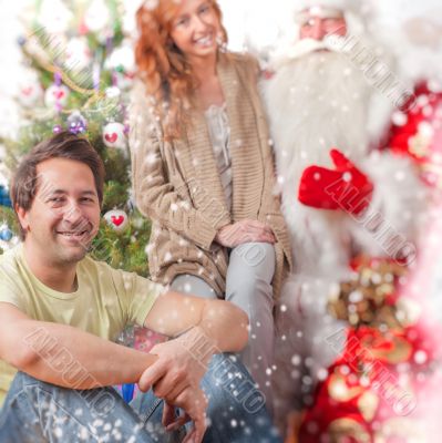 Happy family embracing and sitting on the floor in front of Chri