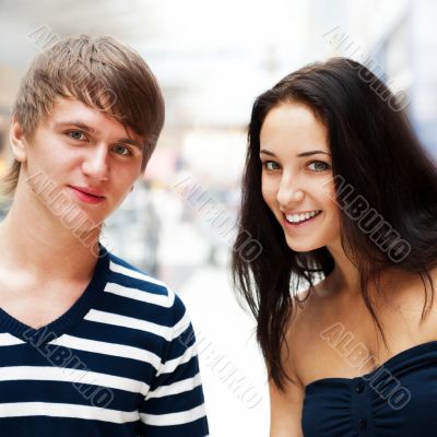 Portrait of young couple embracing at shopping mall and looking 