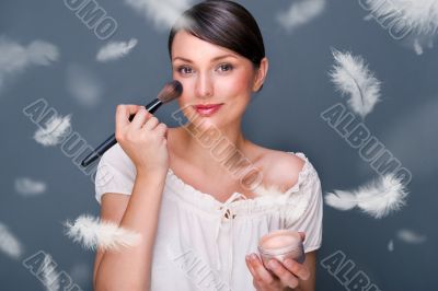 Portrait of a Beautiful woman applying makeup with brush on her 