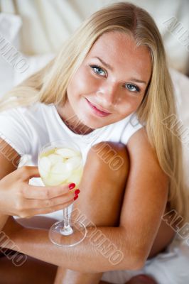 Woman drinking fresh ice tea beverage and looking at camera whil
