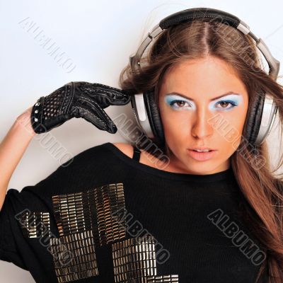 Club style woman with headphones listening to music looking at c