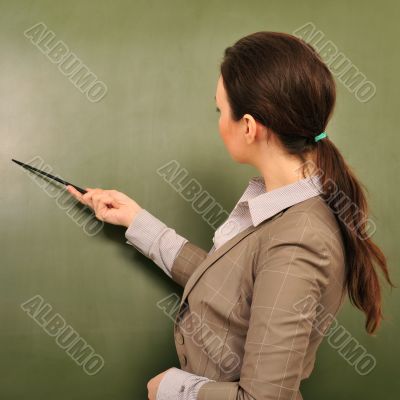 Portrait of young woman teacher standing near blackboard and exp