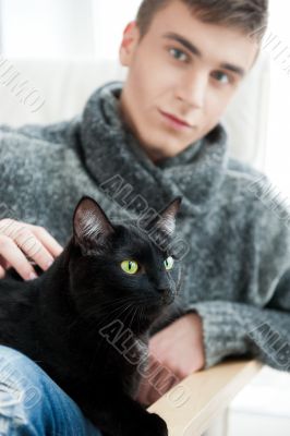 Relaxed man sitting on armchair holding and petting pet cat