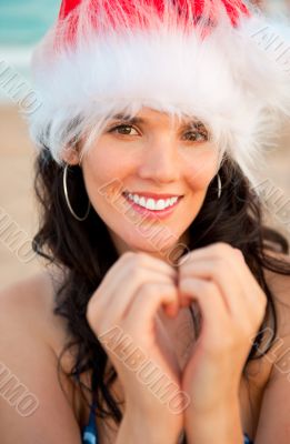 Young beautiful woman wearing christmas hat showing heart shape 