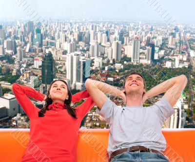 Closeup portrait of adult couple sitting on their sofa against b