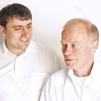 Two men in living room standing against the wall  smiling