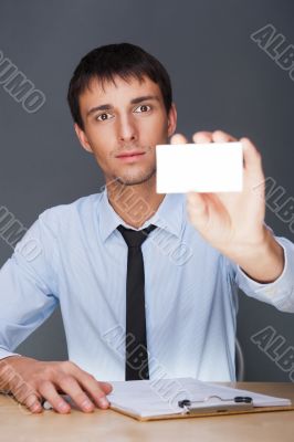Business man handing a blank business card over grey background