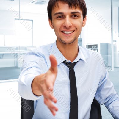 Businessman gives a handshake. Sitting near his laptop at his de