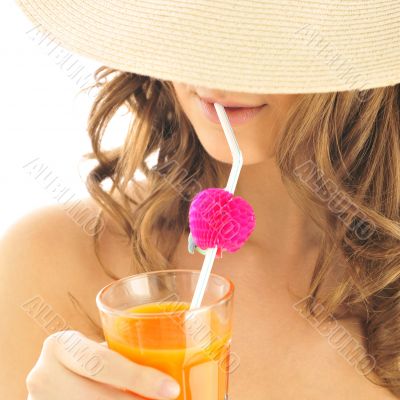 Woman drinking orange juice and wearing summer hat. Vacation con