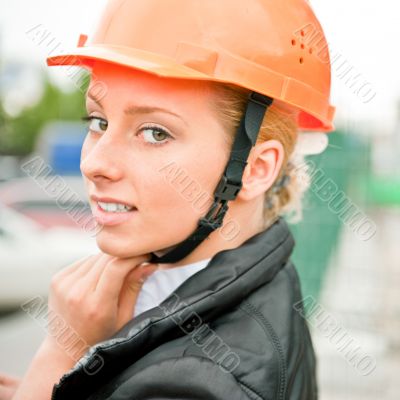 Young architect-woman wearing a protective helmet standing on th