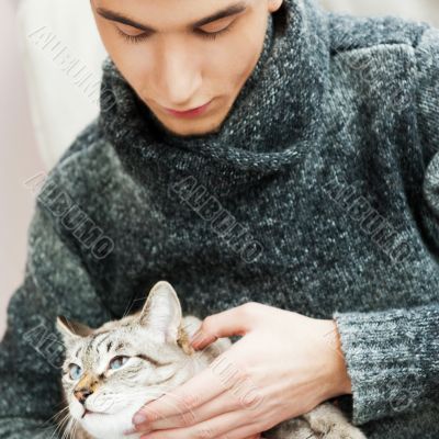 Relaxed man sitting on armchair holding and petting pet cat