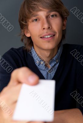 Business man handing a blank business card over grey background