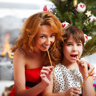 Mother and her daughter sitting together near christmas tree