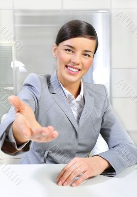 Business woman gives a handshake at her office. Vertical shot.
