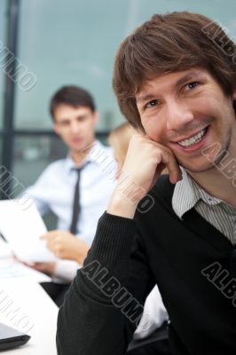 Portrait of a young business man sitting by his laptop in the of