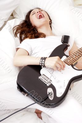 Teen girl holding a guitar like a rock star and enjoying playing