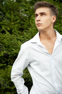 Satisfied smiling businessman standing in the green outdoors.