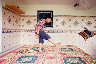 Artistic lifestyle photo of young boy kicking pillow standing on