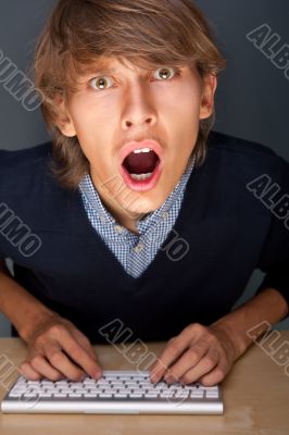 Portrait of young handsome shocked good looking man working usin