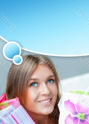 Shopping woman with lots of bags smiles inside mall. She is happ