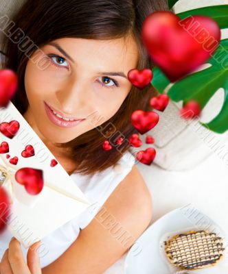 Delighted woman reading a greeting card sitting on the sofa at h