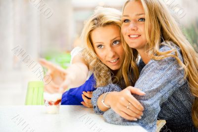 Two beautiful women drinking coffee and chatting at mall cafe.