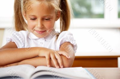 Image of smart child reading interesting book in classroom