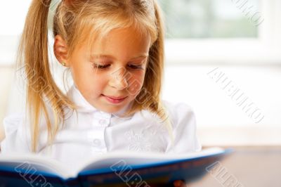 Image of smart child reading interesting book in classroom