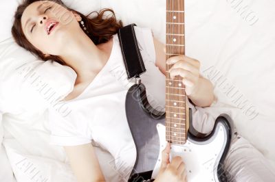 Teen girl holding a guitar like a rock star and enjoying playing
