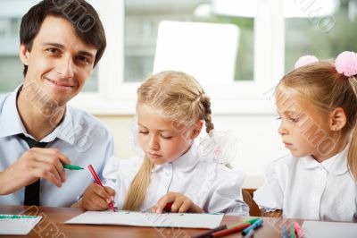 Teacher helping elementary school pupils with their tasks