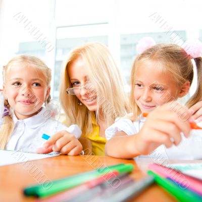 Young pretty teacher helping to her students to make exercise in