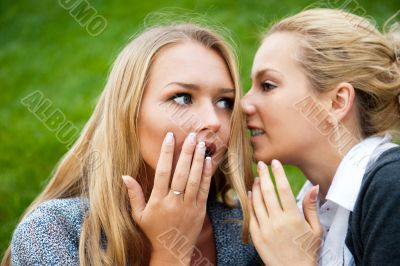 Two women whispering and smiling