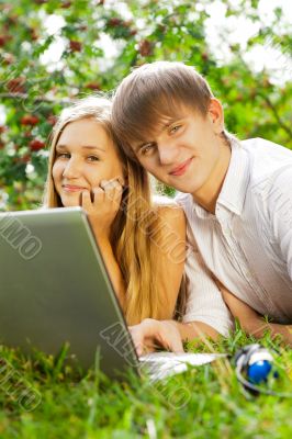 College students using laptop on campus lawn