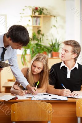 Teacher helping students in school classroom. Horizontally frame