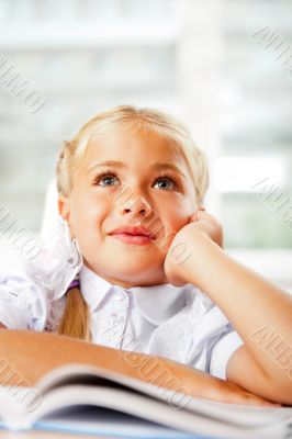 Image of smart child reading interesting book in classroom