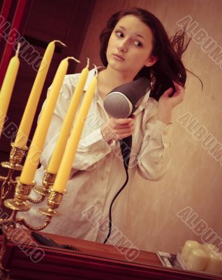 Beautiful woman drying her hair with hairdryer