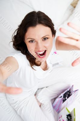 Portrait of young beautiful awake woman with gifts on bed at bed