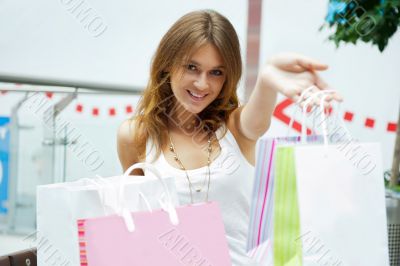 Photo of young joyful woman with shopping bags on the background