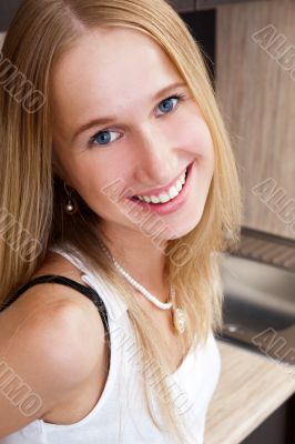 Portrait of beautiful relaxed young woman standing at the kitche