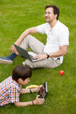 Man and young boy his son sitting outdoors 