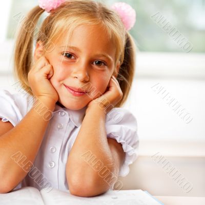 Image of smart child reading interesting book in classroom