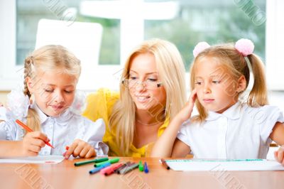 Young pretty teacher helping to her students to make exercise in